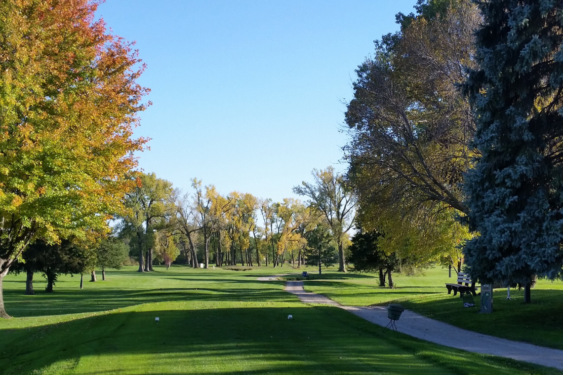 view of golf course green with autumn trees